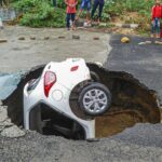 A car stuck after a road caved at Dwarka in New Delhi