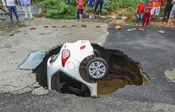 A car stuck after a road caved at Dwarka in New Delhi