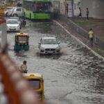 Vehicles move through a waterlogged street after heavy rain in New Delhi