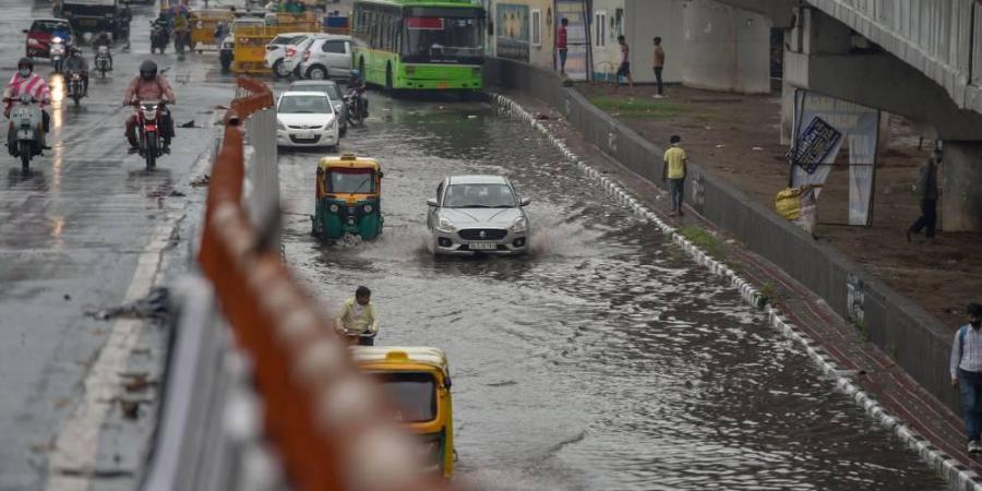 Vehicles move through a waterlogged street after heavy rain in New Delhi