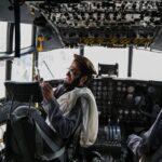 Taliban fighters sit in the cockpit of an Afghan Air Force aircraft at the airport in Kabul.