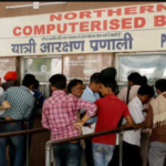 Passengers queue up at a ticket counter at a railway station