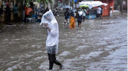 A man covers himself with a plastic sheet amid heavy rainfall in Surat.