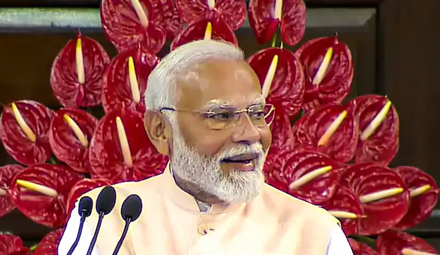 Prime Minister Narendra Modi smiling at an event, receiving greetings on his 74th birthday from various political leaders.