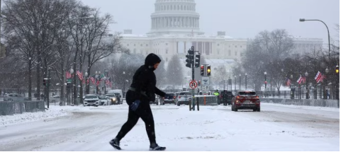 A snow-covered street in the US with cars stuck in icy conditions during a polar vortex-driven winter storm.