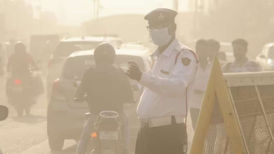 Dense smog covering Delhi skyline with vehicles moving slowly on a polluted morning.