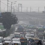Worker spraying water to control dust as Delhi air quality worsens during winter pollution spike.