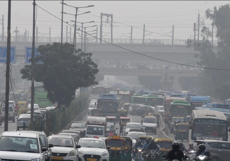 Worker spraying water to control dust as Delhi air quality worsens during winter pollution spike.