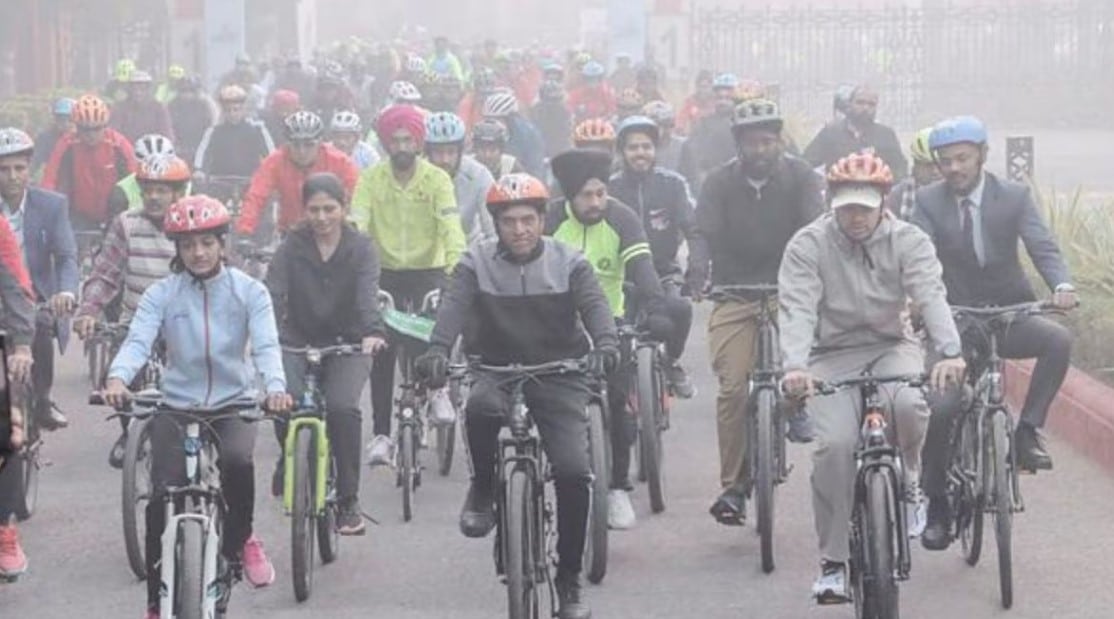 Cyclists commuting on a busy Delhi street, highlighting the need for safer roads and dedicated cycle lanes.